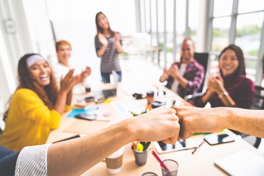 Employees participating in a meeting, expressing excitement with hands in the air