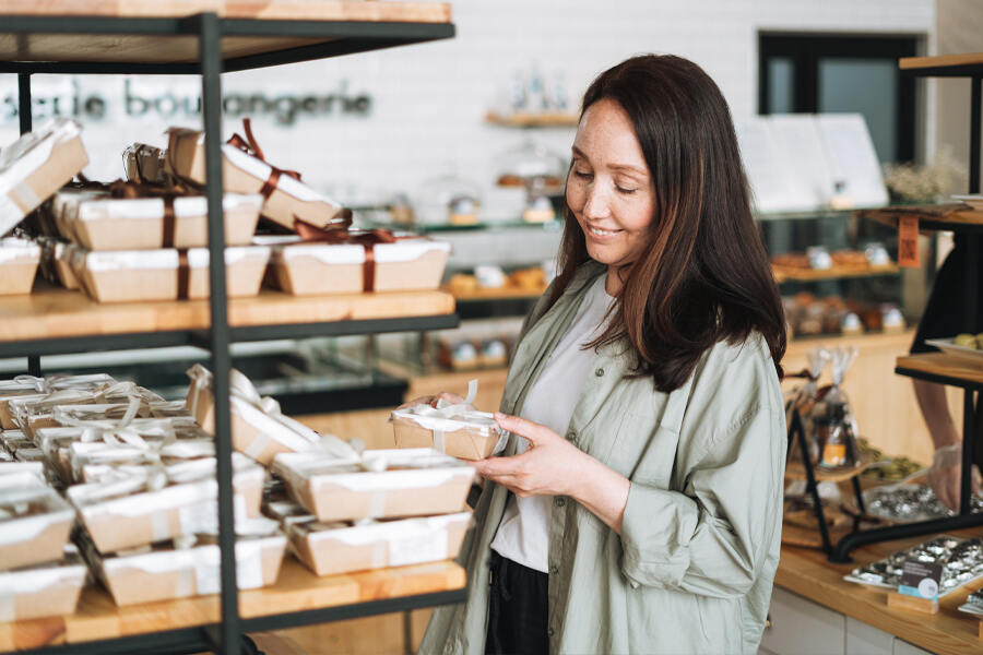 A woman examines a chocolate gift on a shelf, contemplating the perfect choice for a special occasion